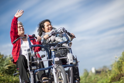 Twee dames lachend op een pris duofiets