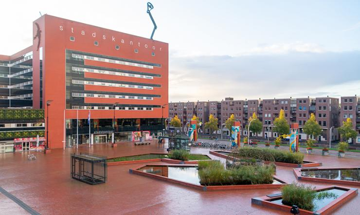 Het rode Lübeckplein in Zwolle na aanpassingen. Je ziet meer groen en mogelijkheid voor ontspanning en activiteiten op het plein dat voorheen alleen uit steen bestond.