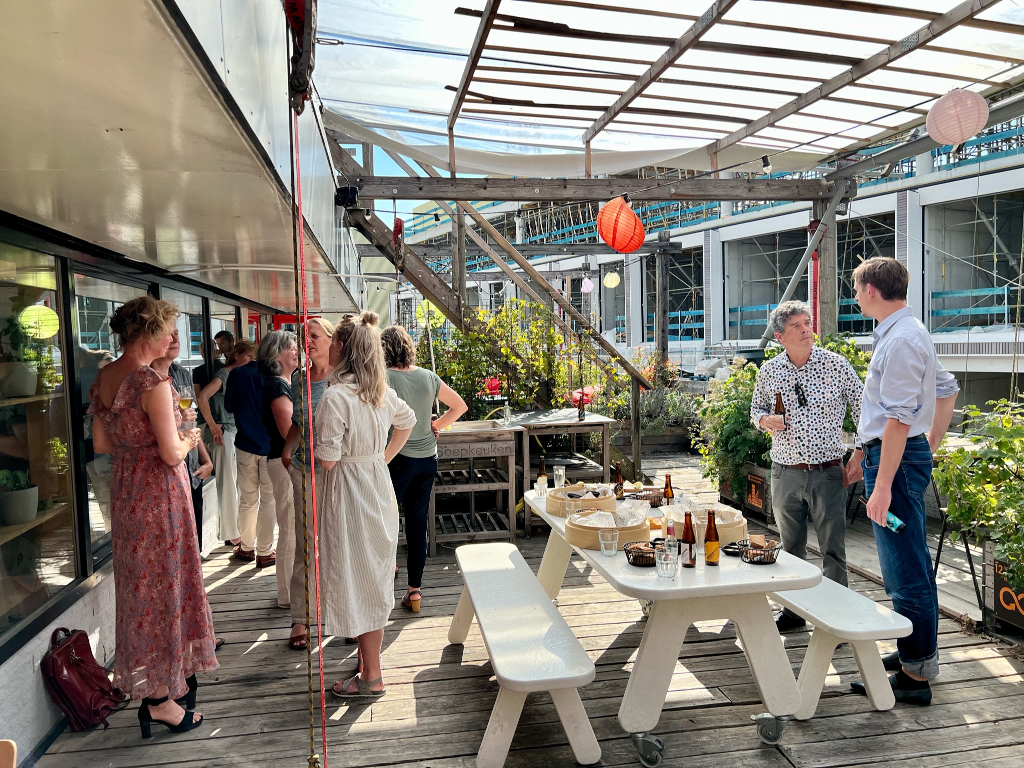 Deelnemers staan op het dakterras te borrelen