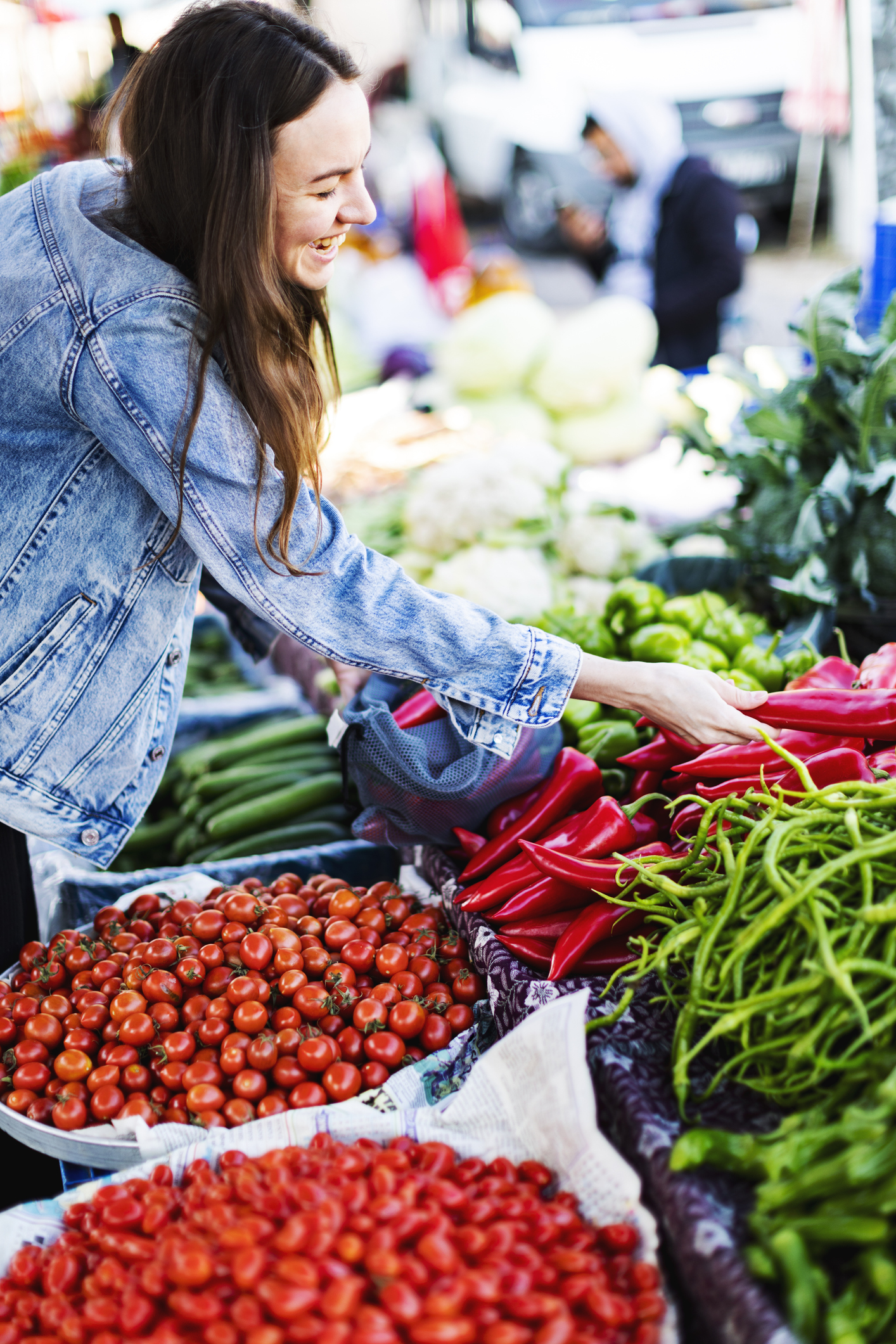 Vrouw pakt paprika’s op markt