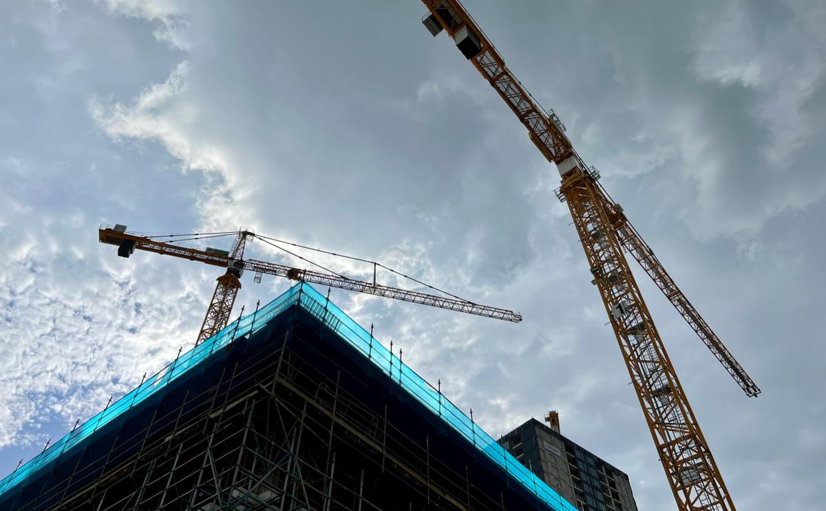 woningbouw van onder gefotografeerd, en staan 2 hijskranen uit te rijzen boven de bouw.