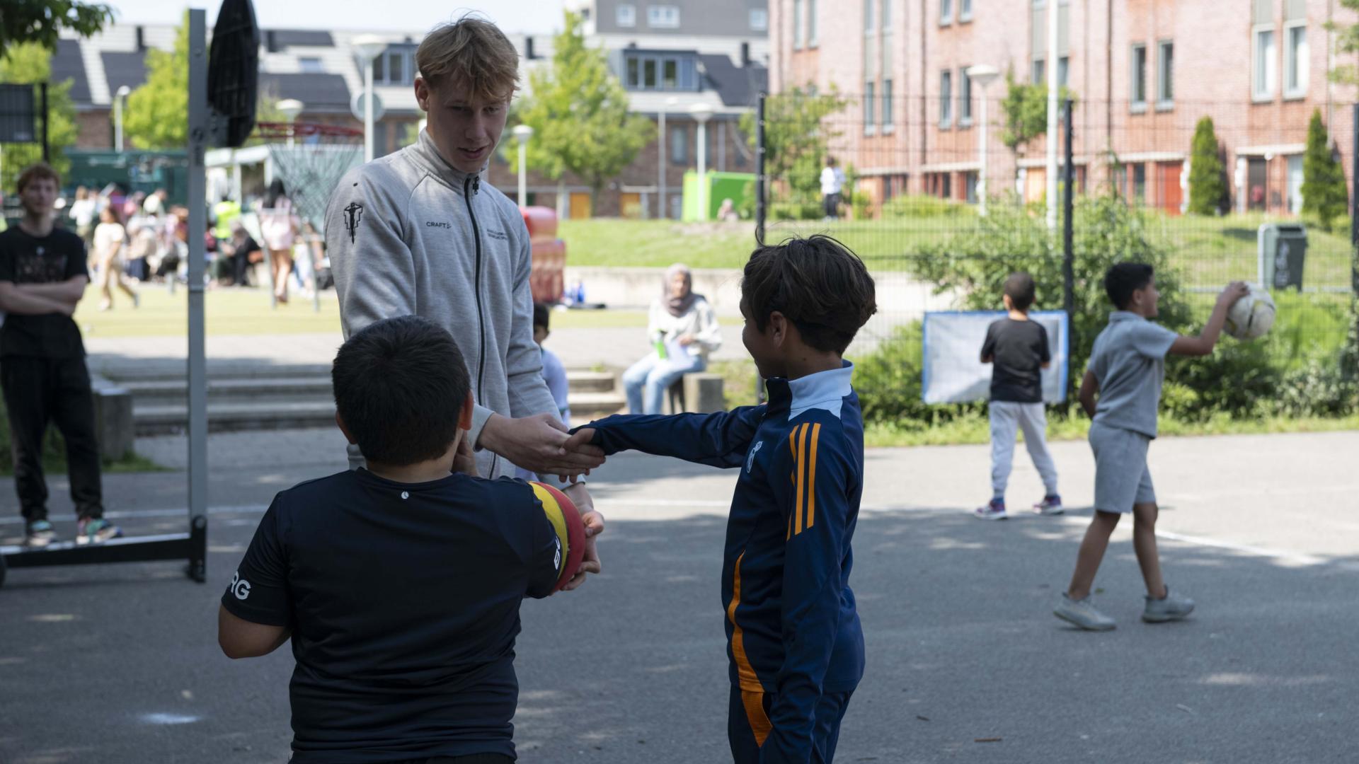 Een sporter praat met twee kinderen over sport