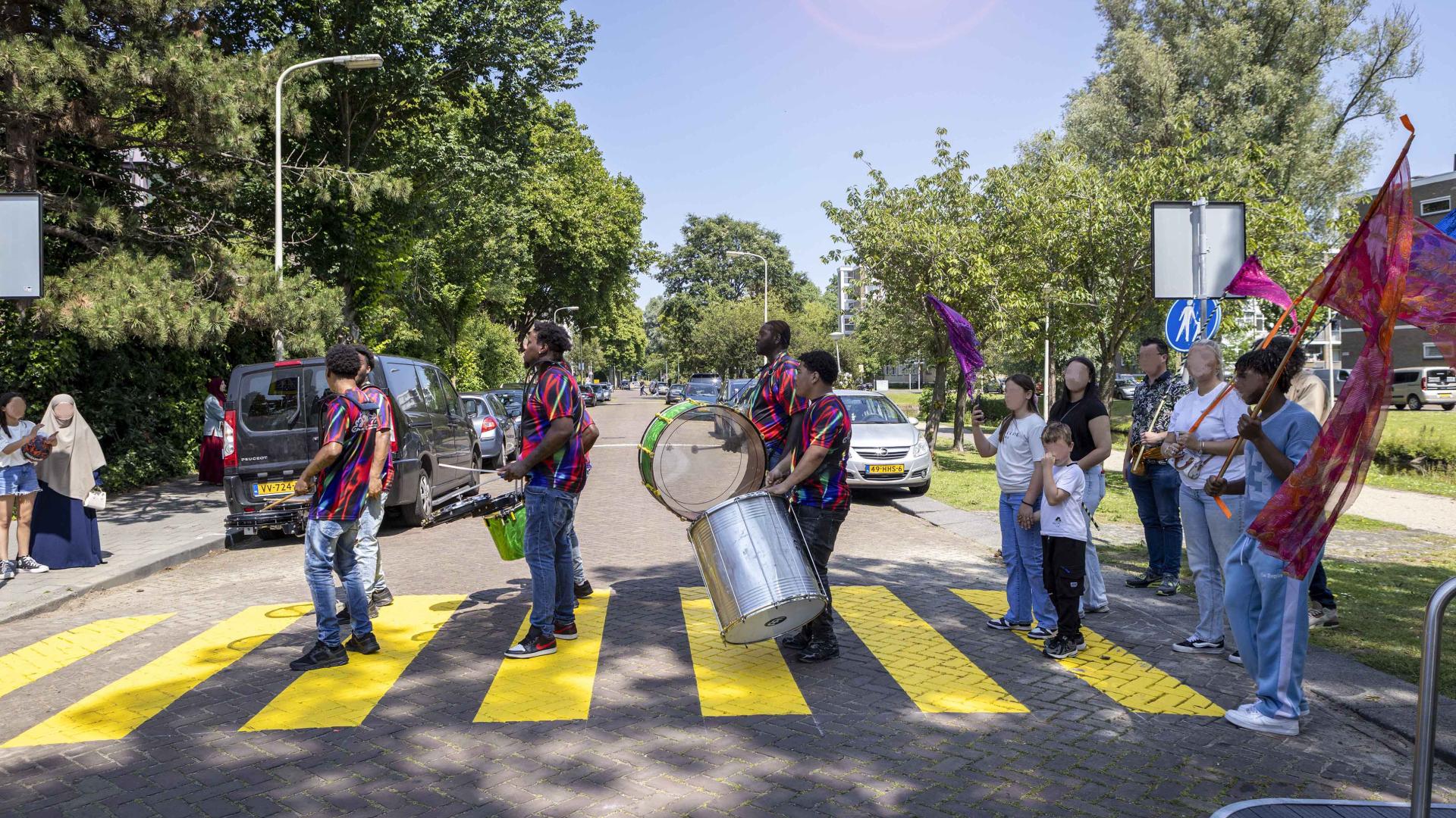 Een fanfare van muzikanten loopt over een zebrapad