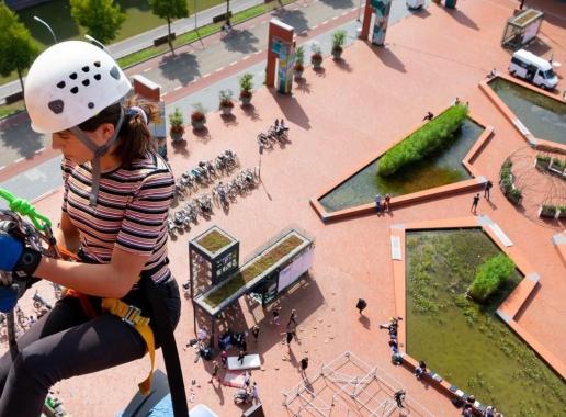 Vrouw hangt van een gebouw (verzekerd) boven het nieuw ontwikkelde rode plein - het Lübeckplein - in Zwolle.