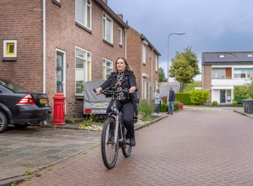 Vrouw fietst in richting van de camera in een bebouwde omgeving