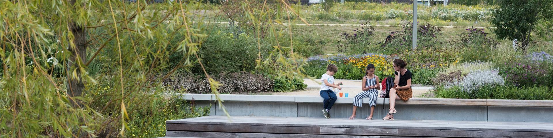 Kinderen en volwassene zitten aan het water ter recreatie in de spoorzone Tilburg