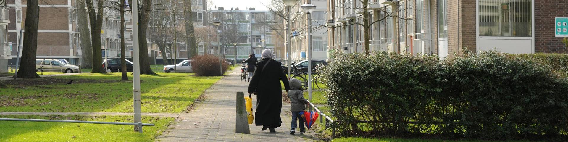 Een vrouw en een kind lopen door een aandachtswijk.