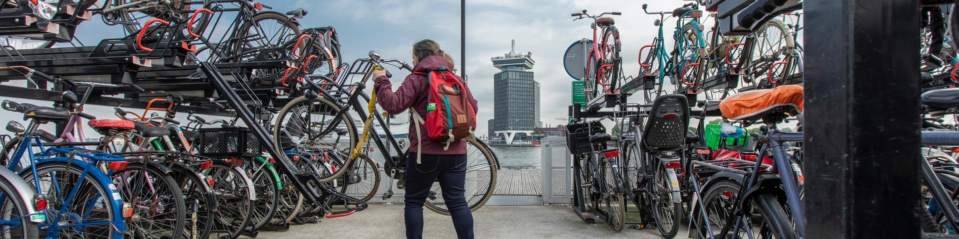 Vrouw zet fiets in rek stalling Amsterdam CS