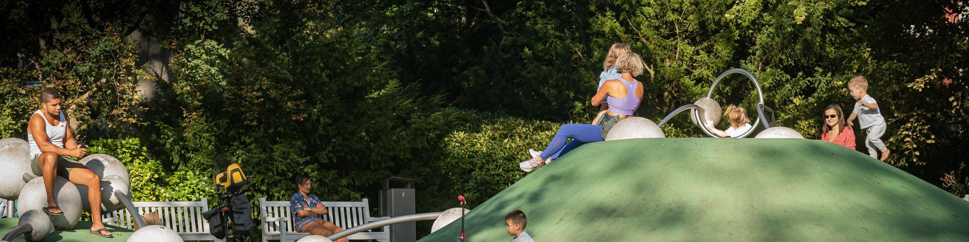 speelplaats in de paleistuin met kinderen en ouders die toekijken