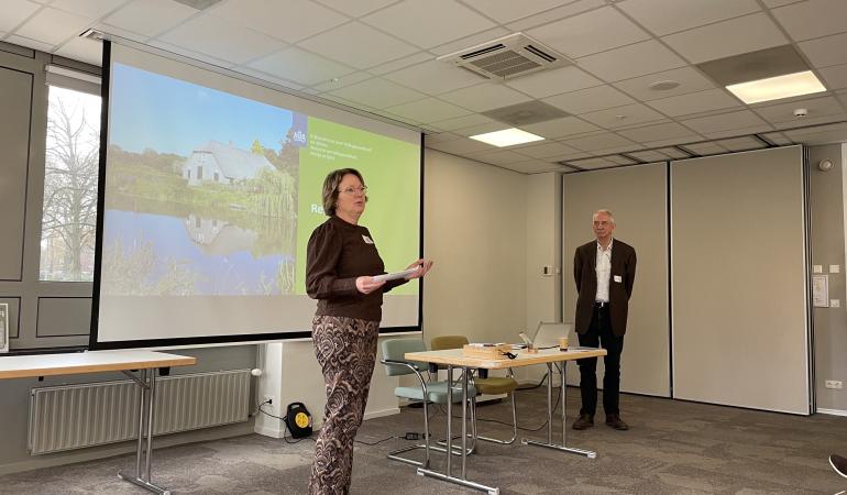 Renske Nijdam (links) staat voor het presentatiescherm en spreekt publiek toe naast Cor Coenrady (rechts)